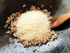 合い挽き肉と玉ねぎを炒めているフライパンに、米を入れる。