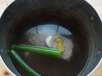 ネギの青い所、生姜、ニンニクを入れて煮込むチャーシュー肉