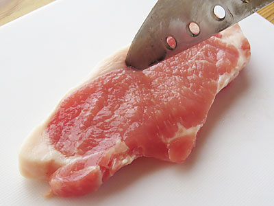 包丁で豚肉の筋を切る