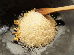 鶏皮を炒めているフライパンに生米を入れる。