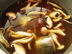 煮こみ中の鍋にうどんつゆの材料と、さばの水煮缶を入れる