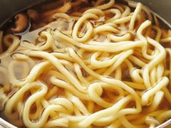 鍋にうどん麺をほぐし入れる