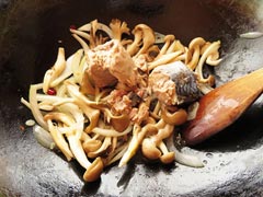 玉ねぎとしめじ、舞茸を炒めているフライパンにサバ缶を入れる