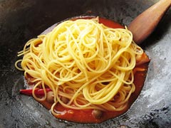 パスタソースの入ったフライパンにゆでたスパゲティを入れる