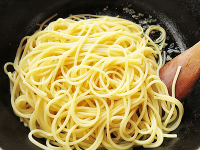 パスタソースの入ったフライパンにパスタ麺を入れる