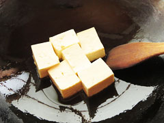 ごま油をひいたフライパンで切り分けた木綿豆腐を焼く