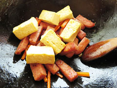 スパムを炒めているフライパンに、焼き目を付けた木綿豆腐を入れる