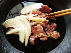 割り下の入ったフライパンで玉ねぎと豚肉を煮る