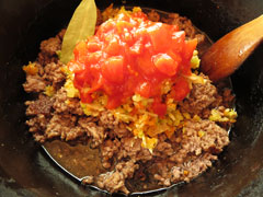 ひき肉を煮込んでいる鍋にソフリットとローリエ、トマト缶、醬油を入れる。