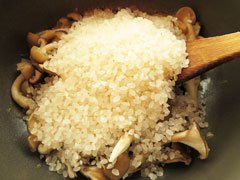 きのこを炒めている鍋に生米を入れる。