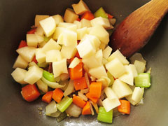 野菜を炒めている鍋にじゃがいもを入れる。
