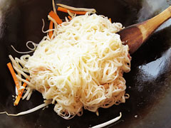 にんじんともやしを炒めているフライパンに、ツナ缶を混ぜた素麺を入れる。