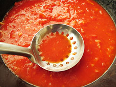 穴あきお玉でトマトを潰しながら煮込む。