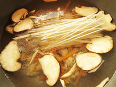 材料を炒めている鍋に水と春雨、鶏ガラスープの素、醤油、酢を入れる。