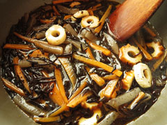 材料を炒めている鍋に、だし汁と調味料を加える。