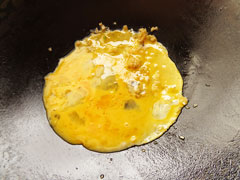 にんにくを炒めている中華鍋に溶き卵を入れる。