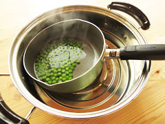 茹で上がったグリーンピースを小鍋に入れたまま、水を張った大鍋に入れる。
