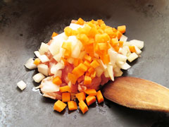 にんにくを炒めているフライパンに、切り分けた玉ねぎとにんじん、鶏肉を入れる。
