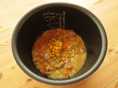 炒めた米と具、コーン缶、水、コンソメの入った炊飯器の内釜。
