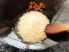 鶏皮を炒めているフライパンに生米を入れる。