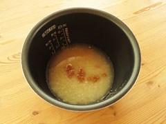 炊飯器の内釜に炒めた米と鶏がらスープの素を溶かした水を入れる。