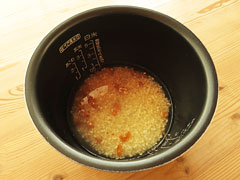炒めた米の入った炊飯器の内釜に、鶏がらスープの素を溶かした水を入れる。