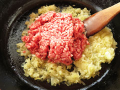 玉ねぎを炒めているフライパンにひき肉を入れる。