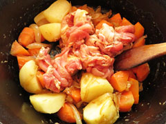 野菜を炒めている鍋に豚肉を入れる。