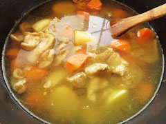 野菜と豚肉を炒めている鍋に水とコンソメを入れる。