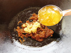 オニオンペーストを炒めているフライパンにすりおろしたにんにくと生姜、マーマレードジャムを入れる。