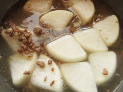 ひき肉と大根を炒めている鍋に、だし汁を注ぐ。
