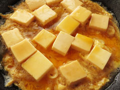 豆腐を煮ているフライパンに溶き卵2/3を回し入れる。