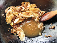 合い挽き肉と長ネギを炒めているフライパンに、スパゲッティの茹で汁を入れる。