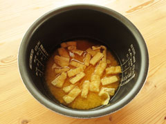 米と調味料、だし汁の入った炊飯器の内釜に、せん切り生姜と油揚げを入れる。