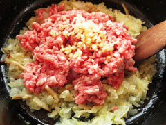 玉ねぎを炒めている鍋に合い挽き肉と生姜を入れる。