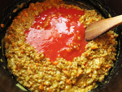 具材を炒めている鍋にトマトジュースを加える。