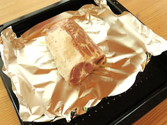 アルミホイルを敷いた天板に豚肩ロースのブロック肉を置いてオリーブオイルを塗る。