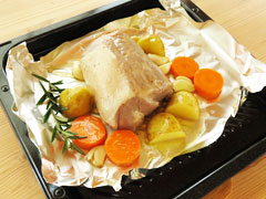 豚肩ロースのブロック肉の回りにじゃがいもとにんじん、にんにく、ローズマリーを並べる。