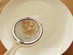 細かい網を使って皿に小麦粉をふる。