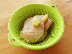 ブライン液に漬けた鶏むね肉とにんにくを、ザルに入れて水気を切る。