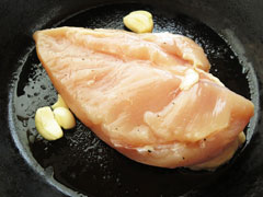バターを溶かしたフライパンに、皮面を下にした鶏むね肉とにんにくを入れて焼く。