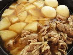 大根を炒めているフライパンに、豚肉とゆで卵、だし汁、調味料を入れる。