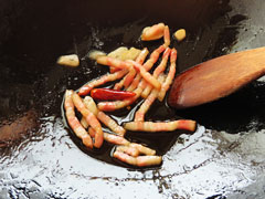 ベーコンとにんにくを炒めているフライパンに鷹の爪を加える。