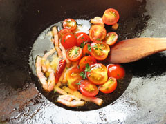 ミニトマトを炒めているフライパンに、スパゲティの茹で汁お玉1杯とパセリのみじん切りを加える。