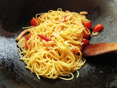 スパゲティを加えてざっと炒めた、ミニトマトとベーコンのパスタ。