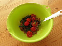 かき混ぜた納豆の入ったボウルに、切り分けたミニトマトとしその葉を入れる。