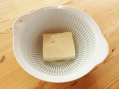 ざるに木綿豆腐を入れて水を切る。