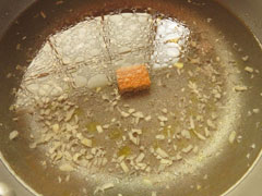 にんにくを炒めている鍋に、水とコンソメ、白ワインを加える。