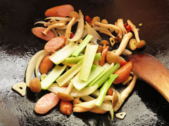 具を炒めているフライパンに小松菜の茎を入れる。