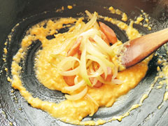 スクランブルエッグを炒めているフライパンに、ウインナーと玉ねぎを入れる。